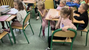 dzieci siedzą przy stolikach w bibliotece