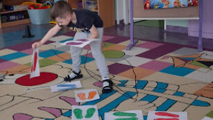 dziecko układa obrazki na dywanie
