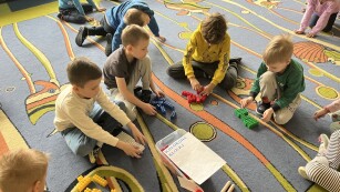 dzieci siedzą na dywanie i układają klocki